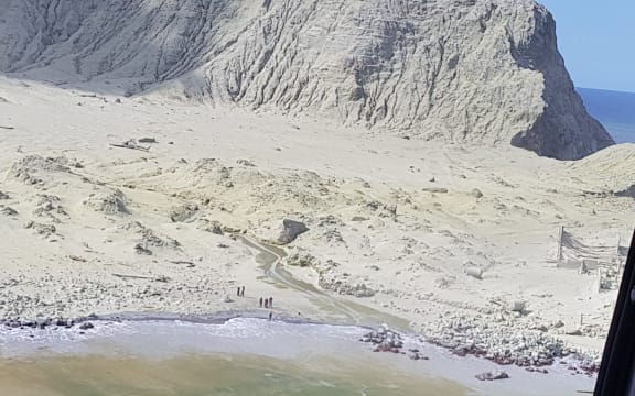 The landing bay on Whakaari/White Island, where people and a helicopter can be seen.