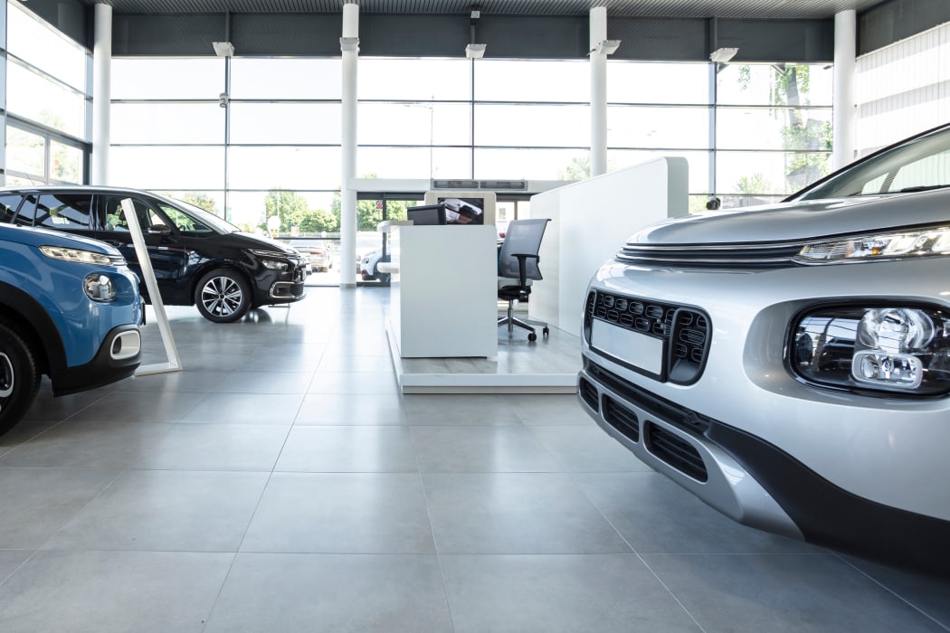 Car seller's station and parked cars in the interior of a modern dealership
