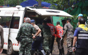 Thai soldiers and paramedics help a rescued boy on a stretcher to an ambulance outside the Tham Luang cave.