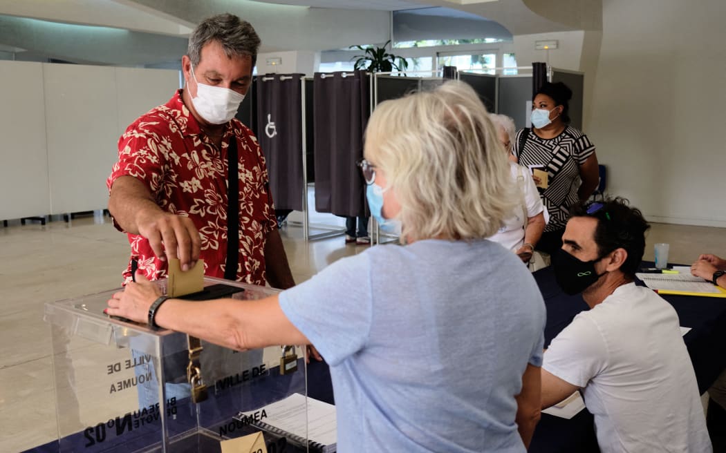 A citizen casts his ballot at a polling station for the referendum on independence at the City Hall in Noumea, on the French South Pacific territory of New Caledonia on December 12, 2021.