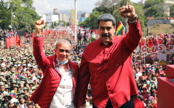 (FILES) Handout photo released by the Miraflores presidential palace press office showing Venezuela's President Nicolas Maduro (R) accompanied by his wife Cilia Flores raising their clenched fists during a civil-military parade to commemorate the 20th anniversary of the coup that briefly removed late Venezuelan president (1999-2013) Hugo Chavez from power, in Caracas on April 13, 2022. President Donald Trump said on January 3, 2026, that US forces had captured Venezuelan leader Nicolas Maduro after launching a "large scale strike" on the South American country. "The United States of America has successfully carried out a large scale strike against Venezuela and its leader, President Nicolas Maduro, who has been, along with his wife, captured and flown out of the Country," Trump said on Truth Social. (Photo by Venezuelan Presidency / AFP) / RESTRICTED TO EDITORIAL USE-MANDATORY CREDIT - AFP PHOTO / VENEZUELAN PRESIDENCY - NO MAFRKETING - NO ADVERTISING CAMPAIGNS - DISTRIBUTED AS A SERVICE TO CLIENTS