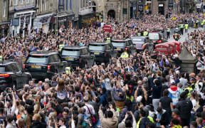 Members of the public watch the hearse carrying the coffin of Queen Elizabeth II, as it is driven through Edinburgh towards the Palace of Holyroodhouse, on September 11, 2022.