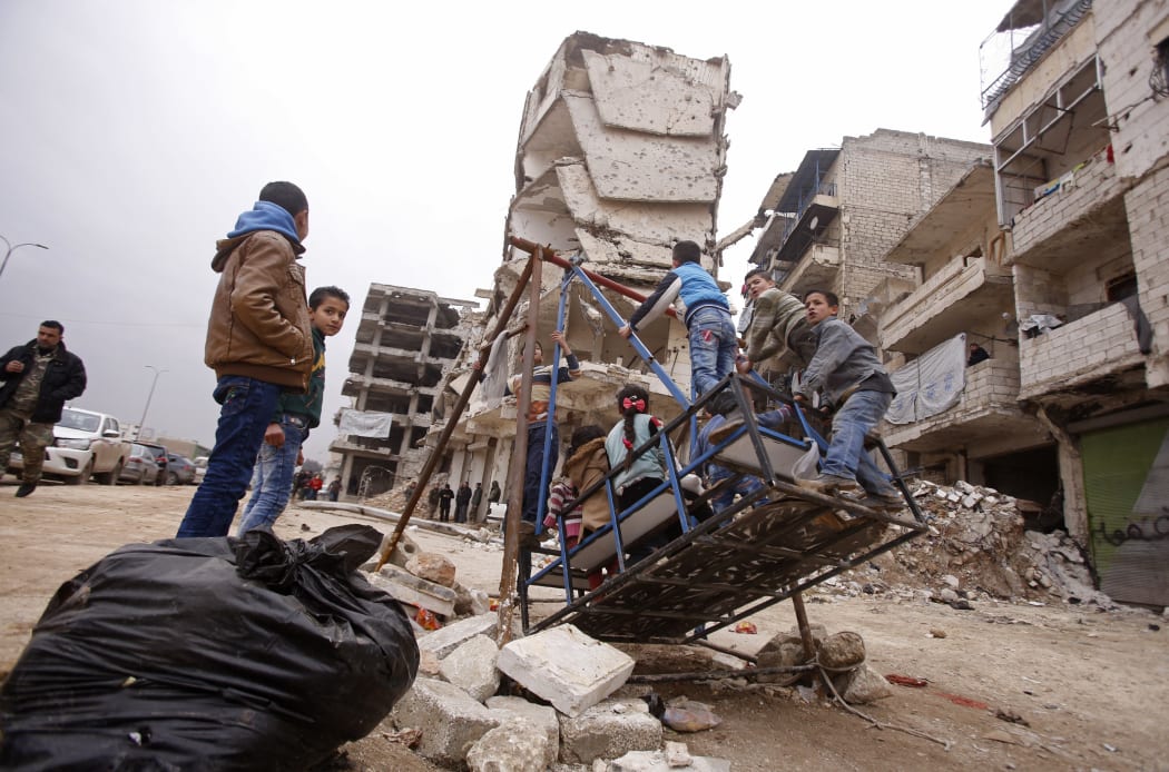 Syrian children play on a swing in the government-held part of Aleppo's Salaheddin neighbourhood on December 16, 2016. The Syrian government suspended the evacuation of civilians and fighters from the last rebel-held parts of Aleppo, leaving thousands of people trapped and uncertain of their fate.