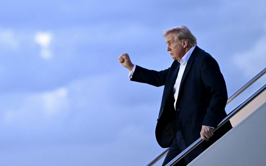 US President Donald Trump raises a fist as he steps off Air Force One at Palm Beach International Airport in West Palm Beach, Florida, on April 11, 2025. Trump is heading to Palm Beach to spend the weekend at his Mar-a-Lago resort. (Photo by Mandel NGAN / AFP)