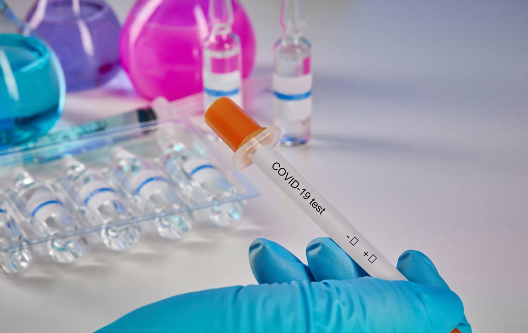 Hand in blue disposable glove holding testing kit. Medical flasks with colorful chemical reagents. Ampoules with liquid and syringe isolated on white. Coronavirus laboratory research.