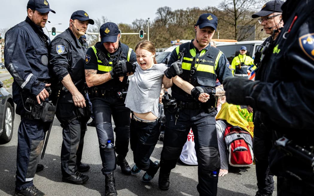 Swedish climate activist Greta Thunberg (C) is arrested during a climate march against fossil subsidies near the highway A12 in the Hague, on April 6, 2024. Dozens of police officers, some on horseback, blocked protesters from reaching the A12 arterial highway into the Dutch seaside city, the scene of previous actions organised by the Extinction Rebellion (XR) group (Photo by Ramon van Flymen / ANP / AFP) / Netherlands OUT