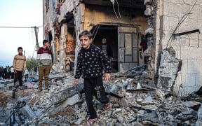 People walk through the rubble of a building heavily damaged by Israeli bombardment, in Rafah in the southern Gaza Strip on 11 February, 2024, amid the ongoing conflict between Israel and the Palestinian militant group Hamas.