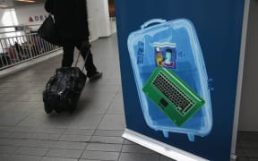 Passenger walks past sign showing x-ray screening.