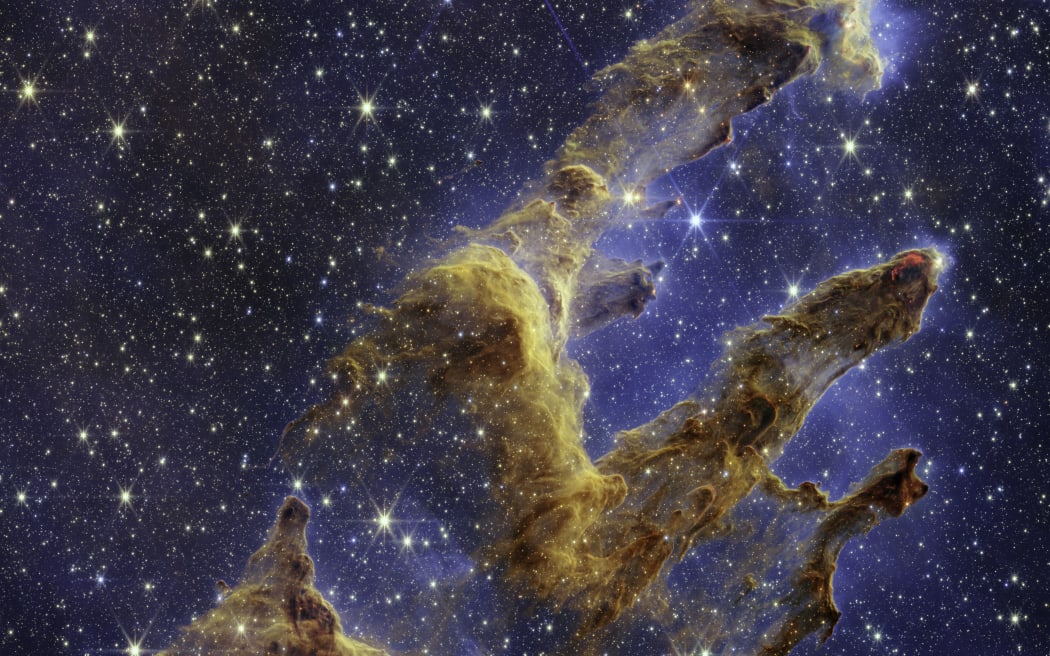 This handout photo provided by NASA on October 19, 2022 shows the Pillars of Creation that are set off in a kaleidoscope of color in NASA’s James Webb Space Telescope’s near-infrared-light view. - The pillars look like arches and spires rising out of a desert landscape, but are filled with semi-transparent gas and dust, and ever changing. This is a region where young stars are forming – or have barely burst from their dusty cocoons as they continue to form. (Photo by Handout / NASA/ESA/CSA / AFP) / RESTRICTED TO EDITORIAL USE - MANDATORY CREDIT "AFP PHOTO / NASA/ESA/CSA " - NO MARKETING NO ADVERTISING CAMPAIGNS - DISTRIBUTED AS A SERVICE TO CLIENTS