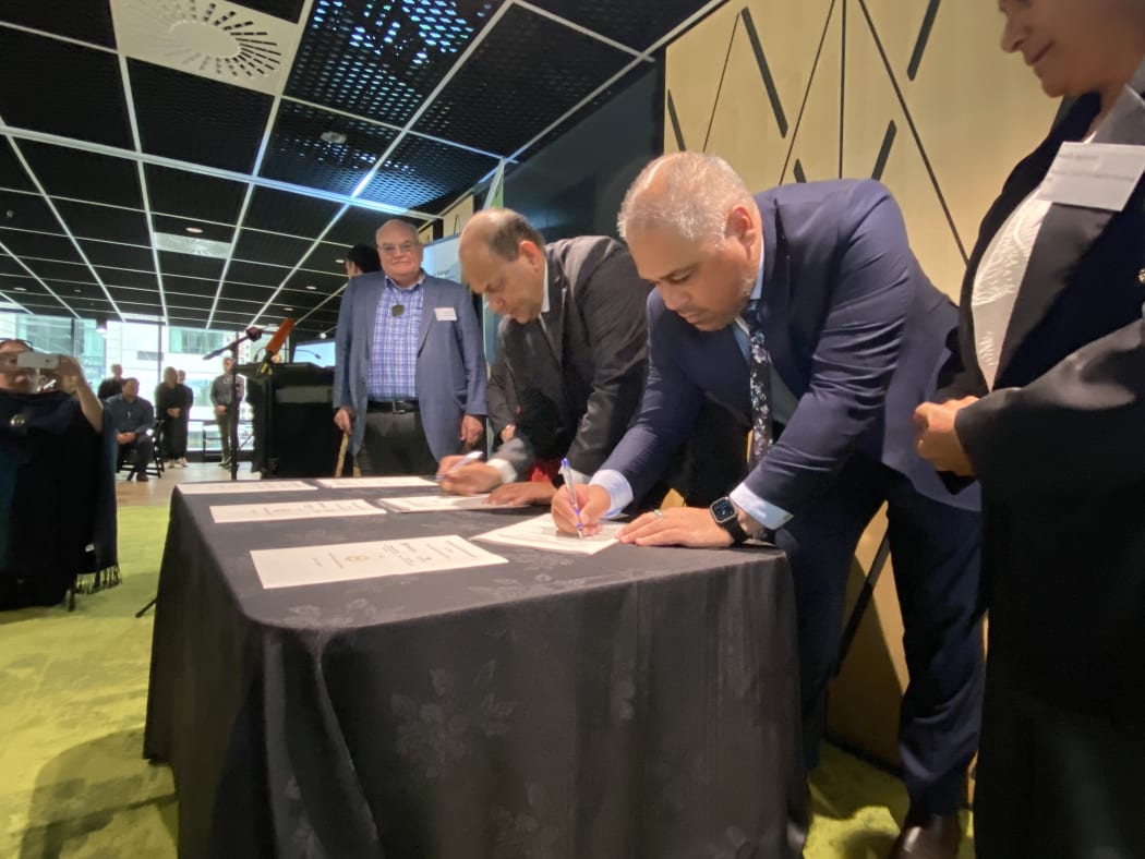 Associate Housing Minister Peeni Henare, foreground, signs a new housing agreement.