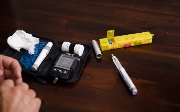 A person tests their blood sugar level at the dining table
