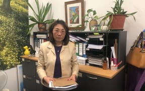 A portrait of employment advocate May Moncur in her office. She is holding casefiles.