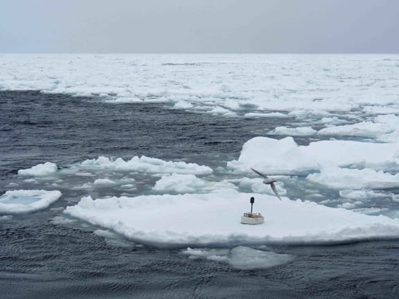 A buoy to measure waves in the Southern Ocean is lowered on to sea ice from the research vessel Aurora Australis.