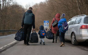 People carrying bags after crossing from Ukraine into Slovakia, 24 February 2022 .