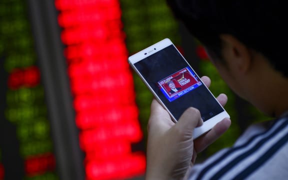 An investor looks at his smartphone showing results from the US presidential election, at a securities company in Beijing on November 9, 2016