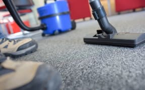 A cleaner uses a vacuum cleaner in an empty office.