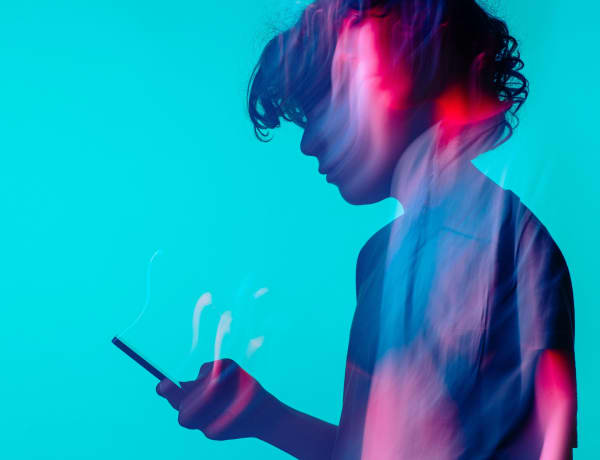 A silhouette of a teenager holding a cell phone.