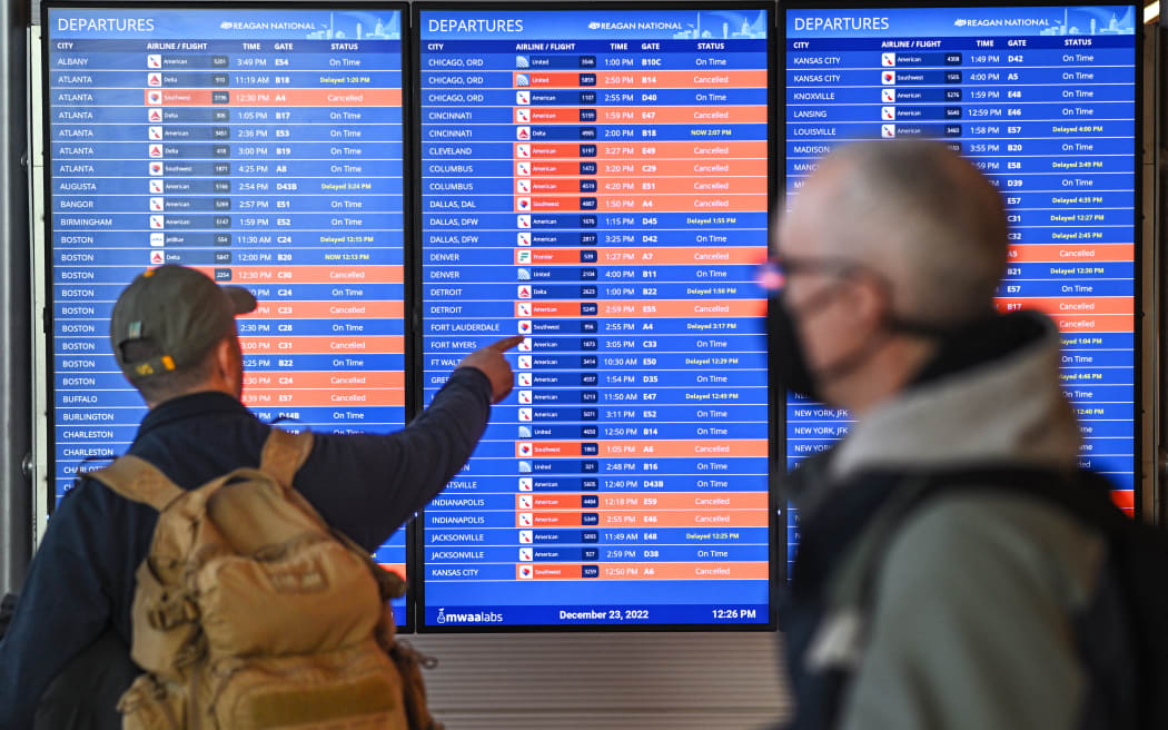 Travelers look at an information board showing flight cancellations and delays at Reagan National airport during a winter storm ahead of the Christmas holiday in Arlington, Virginia.