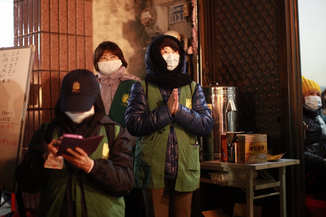 A woman prays outside a room set up for families and friends of victims at the site of a collapsed building in Tainan.