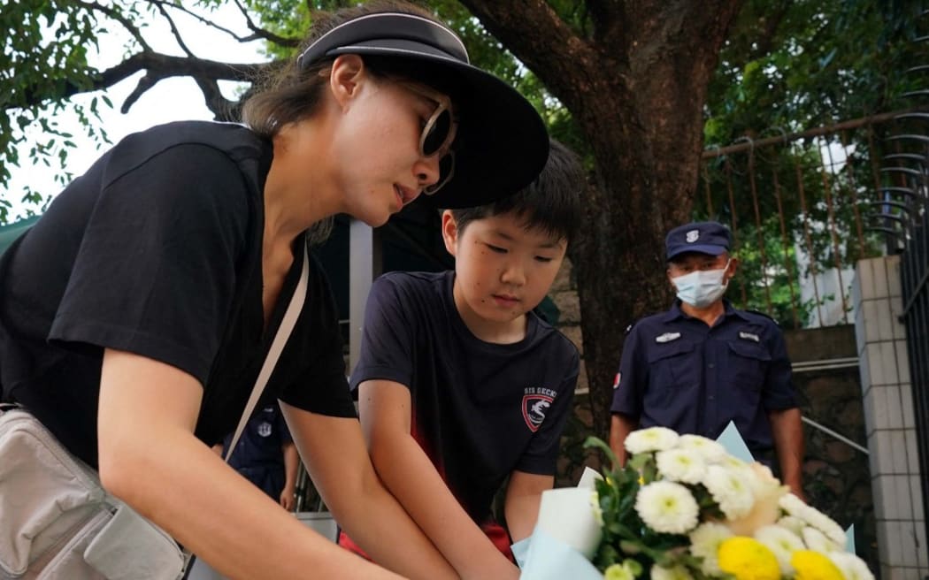 People place flowers at a Japanese school in Shenzhen, September 19, 2024, in Guangdong Province, China. A 10-year-old student at the Japanese school was stabbed on Wednesday by a man and has died one day after the attack.( The Yomiuri Shimbun ) (Photo by Ichirou Ohara / Yomiuri / The Yomiuri Shimbun via AFP)