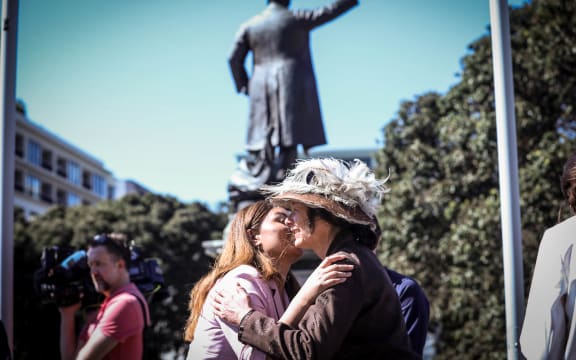 Green Party co-leader Marama Davidson greets a Suffrage Day petition re-enacter in front of a statue of Premier Richard Seddon who opposed women's suffrage