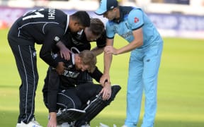 New Zealand's Martin Guptill (C) is assisted by teammates and England's Chris Woakes (R)