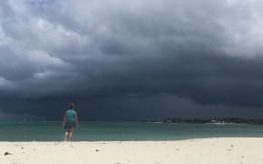 A woman walks on the beach as a storm approaches in Nassau, Bahamas.