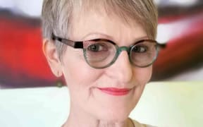 Fifi Colston is a slightly smiling woman with short grey hair and green-rimmed glasses.