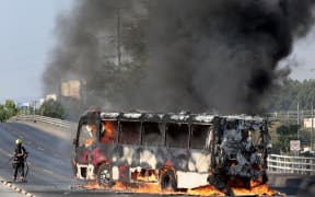 A firefighter extinguishes a burning bus set on fire by organised crime groups in response to an operation in Jalisco to arrest a high-priority security target, at one of the main avenues in Zapopan, state of Jalisco, Mexico, on February 22, 2026. Armed civilians blocked several roads in the state of Jalisco, in western Mexico, following an operation by federal forces in the town of Tapalpa, local authorities reported. Jalisco, which will host four matches of the upcoming 2026 World Cup, is home to the powerful Jalisco New Generation Cartel (CJNG), and has been rocked by several episodes of violence in recent years. (Photo by Ulises Ruiz / AFP)