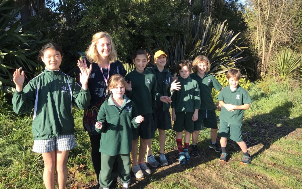 Bianca and students stand in front of the school's native garden area.