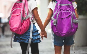 Back to school. Two cute asian child girls with school bag holding hand and walk together in the school