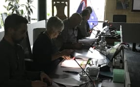 Whangārei District Council councillor Marie Olsen uses her cellphone after the this morning's power cut plunged Te Iwitahi council chambers into near darkness
(Photo Susan Botting Local Democracy Reporter Northland
