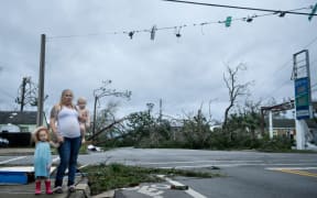 A woman and her children stand near a destroyed gas station after Hurricane Michael in Panama City.