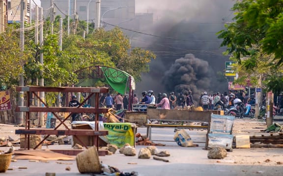This photo taken and received courtesy of an anonymous source via Facebook on 22 March 2021 shows burning barricades in the distance during a crackdown by security forces on demonstrations against the military coup in Mandalay.