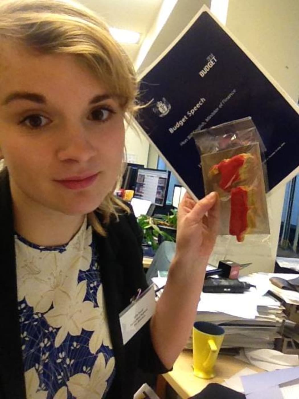 Elle holding the budget documents and a sugar cookie shaped like New Zealand