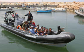Migrants rescued by Tunisia's national guard during an attempted crossing of the Mediterranean by boat arrive at the port of el-Ketef in Ben Guerdane in southern Tunisia  on June 27, 2021. - Tunisia's defence ministry said  its navy had rescued 178 migrants