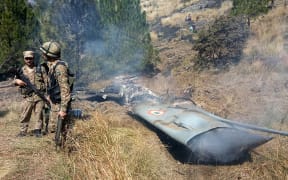 Pakistani soldiers stand next to what Pakistan says is the wreckage of an Indian fighter jet shot down in Pakistan-controlled Kashmir.