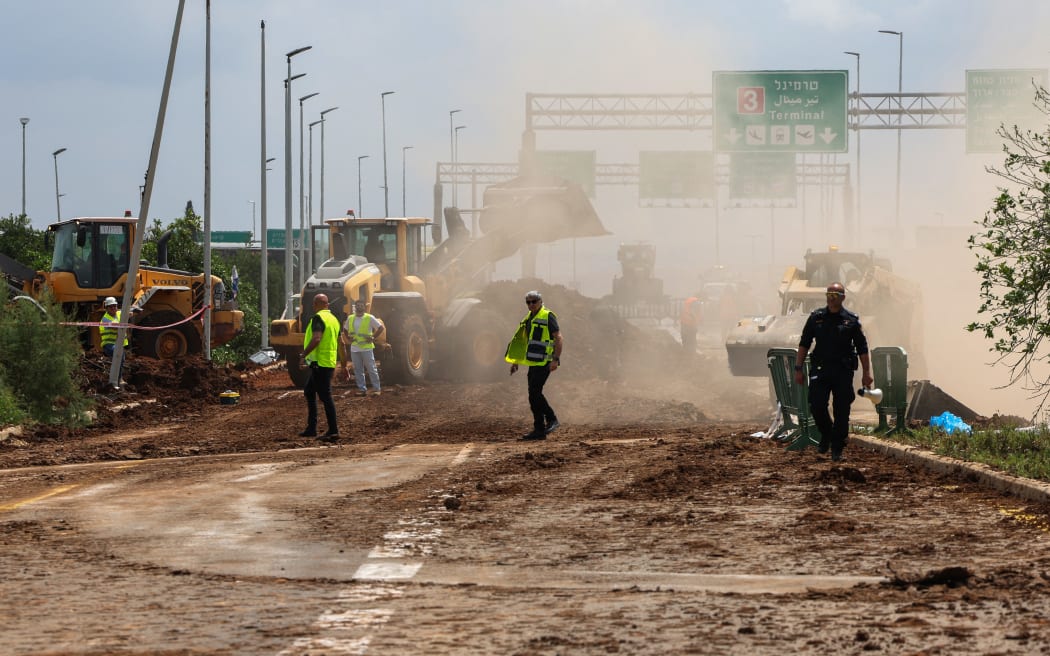 Israeli emergency services clear a road outside Israel's Ben Gurion airport after a missile launched from Yemen struck near the facility on May 4, 2025.