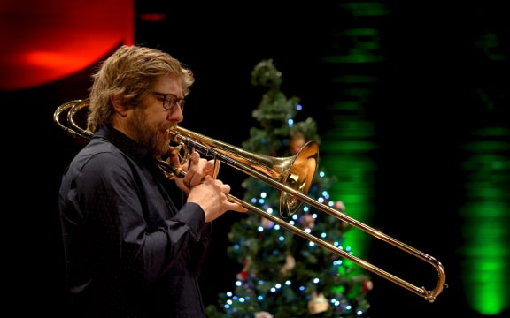 David Bremner playing trombone in front of a Christmas tree