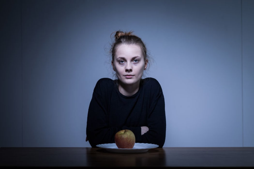 A photo of a girl eating only an apple for dinner