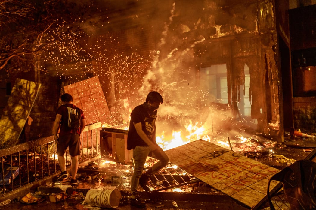 Protesters walk past burning debris outside the Third Police Precinct on May 28, 2020 in Minneapolis, Minnesota, during a protest over the death of George Floyd.
