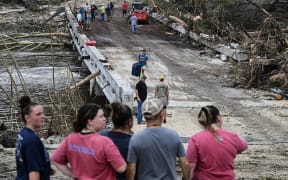 People look on as law enforcement and volunteers continue to search for missing people near Camp Mystic, the site of where at least 20 girls went missing after flash flooding in Hunt, Texas, on July 5, 2025. Rescuers were on Saturday searching for more than 20 girls missing from a riverside summer camp in the US state of Texas, after torrential rains caused devastating flooding that killed at least 27 people -- with more rain on the way. "So far, we've evacuated over 850 uninjured people, eight injured people and have recovered 27 deceased fatalities at this time. Of these 27, 18 are adults, nine are children," said Kerr Country Sheriff Larry Leitha on July 5. (Photo by RONALDO SCHEMIDT / AFP)