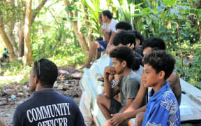 A community officer speaks with youth while watching a sports event in Rennell Bellona province.