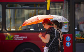 Women using umbrellas to protect against the sun as a heat wave grips London.