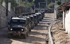 Israeli military vehicles patrol in the Jenin refugee camp, in the occupied West Bank on November 29, 2023, during an ongoing military operation in the camp.