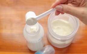 putting powdered milk into a baby bottle