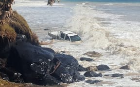 A vehicle at Rainbow Beach swamped by waves in a large swell created by Cyclone Oma.