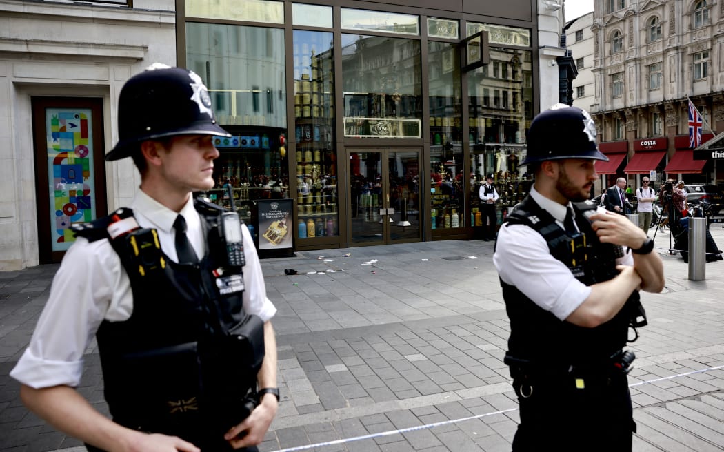 A photograph taken on August 12, 2024 shows police officers standing by a cordoned off area in Leicester square, London. A woman and an 11-year-old girl were hospitalised on August 12 after being stabbed in central London's famous Leicester Square, police said, adding that a man had been arrested. (Photo by BENJAMIN CREMEL / AFP)