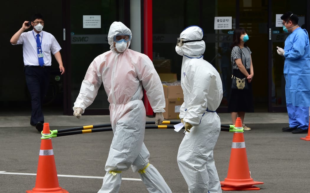 South Korean medical workers in full protective gear walk past in front of the emergency section at the Samsung Medical Centre in Seoul.