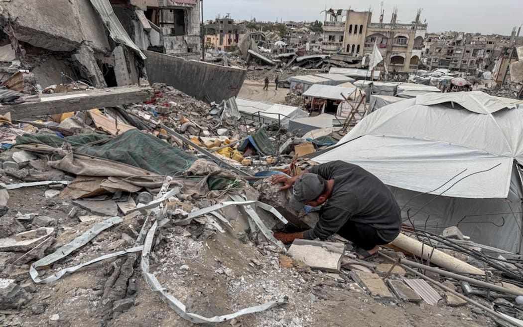 Hamada Alza'anoun picks through the rubble of his destroyed home.